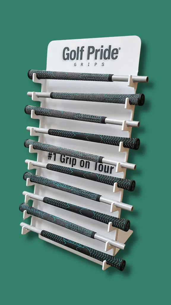 Golf Pride Grip Countertop Display | BAW Plastics Inc. | BAW Plastics Inc. Display stand of Golf Pride golf grips with patterned black-and-teal shafts on a white rack against a green background; sign reads 'Golf Pride Grips' at the top; hashtags '#1 Grip on Tour' visible on one grip.