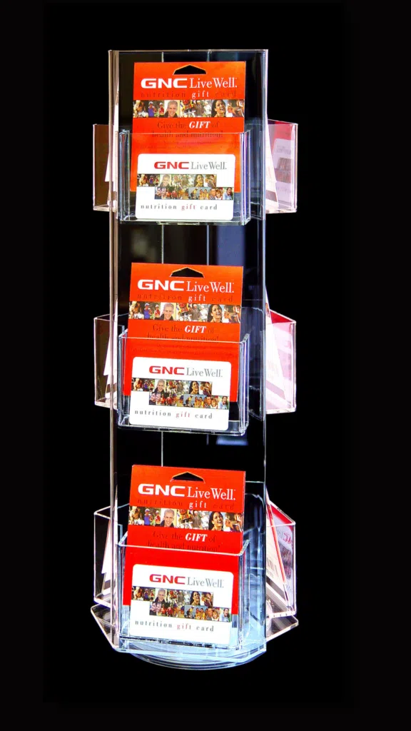 GNC Gift Card Holder | BAW Plastics Inc. | BAW Plastics Inc. Clear multi-tier card rack holding red GNC Live Well nutrition gift cards against a black backdrop.