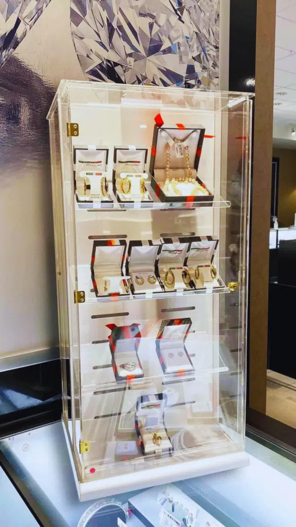 Jewelry Spinner Countertop Display Rack | BAW Plastics Inc. | BAW Plastics Inc. Clear glass jewelry display cabinet with gold rings and bracelets in white presentation boxes on two shelves.