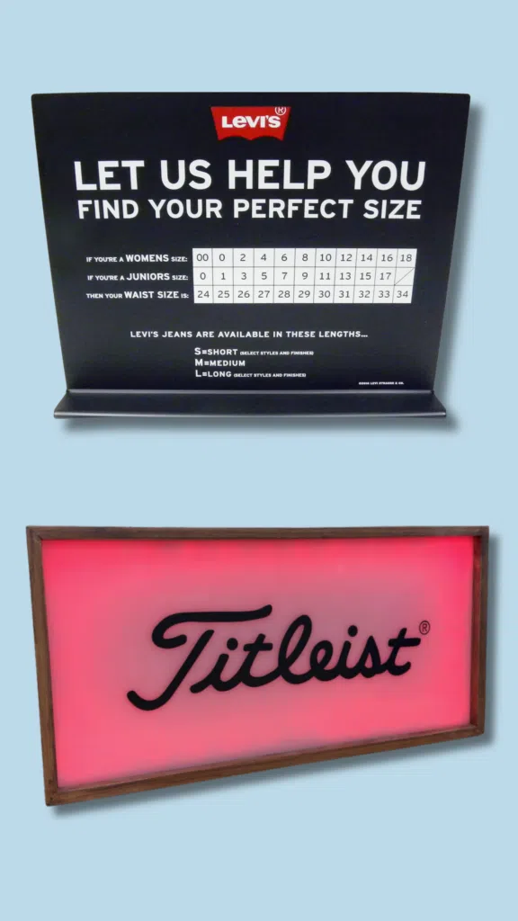 Levi's & Titleist Promotional Signs | BAW Plastics Inc. | BAW Plastics Inc. Levi's promotional sign with 'LET US HELP YOU FIND YOUR PERFECT SIZE' and a size chart, stacked above a pink Titleist display framed in wood against a light blue background.