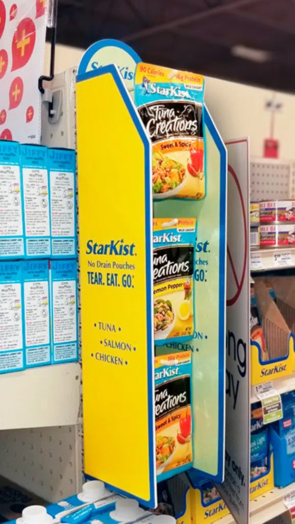 Starkist End Cap Display | BAW Plastics Inc. | BAW Plastics Inc. Bright yellow StarKist display stand in a grocery aisle featuring tuna flavors and blue panels.