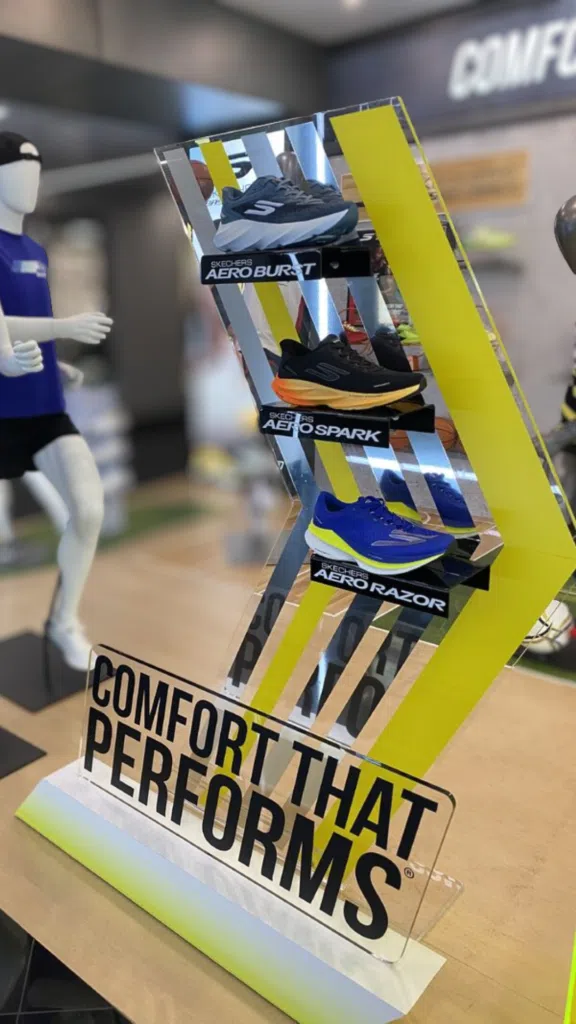 Skechers Floor Display | BAW Plastics Inc. | BAW Plastics Inc. Shoe display in a store featuring Skechers models AeroBoost, AeroSpark, and AeroRazor mounted on a reflective panel with bold yellow accents; signage reads 'COMFORT THAT PERFORMS' in front of the display.